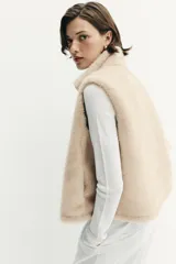 Chaleco de efecto pelo con cuello subido, diseño sin mangas y cierre frontal con cremallera metálica.
