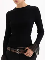 Top de tejido de punto fino color negro, con ajuste al cuerpo, cuello redondo y mangas largas que terminan en puños acampanados con detalle de tejido calado.