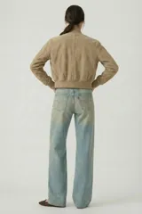 Campera tipo bomber cropped de gamuza sintética color beige, con cuello, puños y ruedo de rib elástico. Cuenta con bolsillos laterales ribeteados y cierre frontal con botones a presión metálicos.
