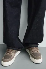 Zapatillas marrones de estilo retro con cordones, capellada de cuero y suela de goma color crema.