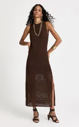 Vestido midi de tejido de punto color chocolate, con cuello redondo, sin mangas y silueta ajustada. Presenta un diseño de tramas caladas alternadas y una abertura lateral en el dobladillo.