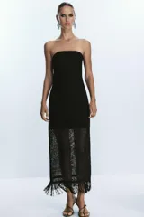 Vestido midi negro de tejido calado con hilo metalizado, escote recto palabra de honor, forro interior y flecos en el ruedo. Cierre lateral con cremallera oculta.