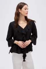 Blusa de poliéster color negro, con diseño holgado, escote en V con solapa y volados que descienden en cascada por el frente. Cuenta con mangas 3/4 con detalles de volados en los puños y en el ruedo.