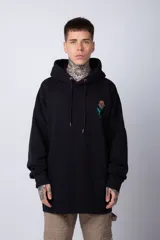 Buzo canguro negro de corte oversize, confeccionado en algodón frizado. Presenta capucha con cordones ajustables, bolsillo frontal tipo canguro y una pequeña estampa de una rosa en el pecho.