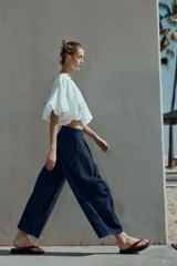 Pantalón tipo culotte de tiro alto confeccionado en denim azul oscuro. Presenta pinzas delanteras, pernera ancha y corta, bolsillos laterales ocultos y cierre frontal con cremallera, botón y ganchos.