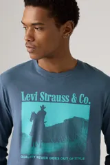 Remera de manga larga Levi's en color azul, con cuello redondo y puños acanalados. Presenta un estampado gráfico frontal en tonos turquesa que muestra la silueta de un vaquero a caballo con el texto 'Levi Strauss & Co.' y la frase 'Quality never goes out of style'.