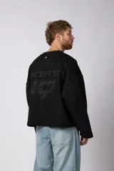 Buzo de cuello redondo confeccionado en tejido rústico con bordes al corte y costuras expuestas. Presenta un diseño boxy con estampado frontal y es reversible, permitiendo su uso por ambos lados.