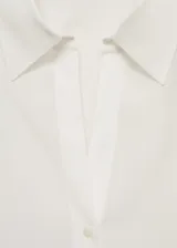 Camisa de corte recto confeccionada en tejido fluido de lyocell, con cuello camisero, cierre frontal de botones, mangas largas con puños abotonados y aberturas laterales.
