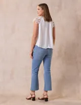 Blusa negra de crepe con apliques de crochet en los hombros. Tiene cuello redondo, mangas cortas y espalda con abertura ojal y botones.