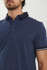 Remera tipo polo de manga corta, color azul marino jaspeado, con cuello y ribetes en las mangas de color azul oscuro y blanco.