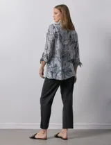 Camisa estampada con hojas en tonos celeste, naranja y verde. Tiene cuello con solapa, abertura central con botones, bolsillos aplicados en la parte delantera y mangas 3/4 con lazo.