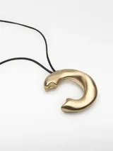 Collar de cordón negro regulable con un dije metálico irregular de color dorado y terminales logotipados.