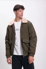 Campera bomber verde de pana con cuello de piel sintética color crema, cierre frontal con cremallera, bolsillos laterales con solapa y puños y cintura elastizados.