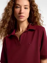 Vestido corto de estilo polo confeccionado en tejido de punto piqué, color bordó. Presenta cuello clásico, escote con abertura y mangas cortas.