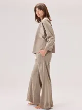 Camisa de manga larga con diseño bicolor en tonos tierra. Presenta un panel frontal y trasero en color beige, contrastado con mangas de un tono marrón más oscuro y textura satinada. Posee cuello redondo y corte recto.
