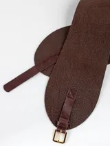 Faja ancha de cuero negro con textura granulada, diseño asimétrico en el cierre y hebilla metálica dorada.