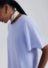 Blusa color violeta con mangas cortas evasé y cuello redondo.