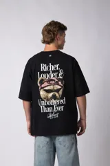 Remera de corte oversize color gris oscuro, confeccionada en algodón premium de alto gramaje. Presenta un diseño minimalista con un pequeño estampado frontal que incluye un oso y el texto 'Richer & Louder VCP'.