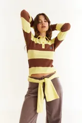 Top de manga larga con diseño de rayas horizontales anchas en amarillo y marrón. Presenta cuello polo con cierre frontal de botones y un pequeño bordado en el pecho.