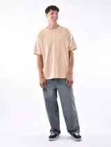 Remera de manga corta color beige, con corte oversize y cuello redondo.