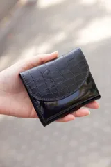 Billetera pequeña negra de cuero con textura tipo cocodrilo y cierre con broche. Hecha a mano en Uruguay.