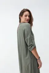 Vestido largo color bordó, tipo camisero, con cuello mao, escote en V y cierre frontal con botones. Mangas largas con vuelta y diseño holgado.