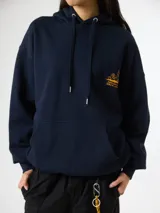 Hoodie azul marino de algodón orgánico, con capucha ajustable con cordón, bolsillo tipo canguro y pequeño estampado gráfico amarillo en el pecho.