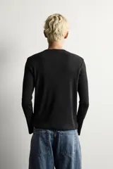 Camiseta de manga larga con cuello redondo, confeccionada en tejido con estructura de canalé y corte relajado.