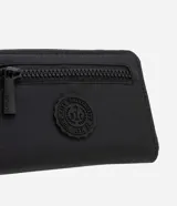 Billetera mediana tipo tarjetero con cierre de cremallera, color negro. Presenta un parche circular con diseño de sello universitario en el frente y tiradores de cremallera con la marca "Satinato".