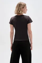 Remera de algodón color marrón oscuro, de manga corta y corte ajustado al cuerpo, con cuello redondo a la base y detalle de bordado con tachas formando el número 14 en el frente.
