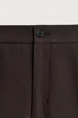 Pantalón de traje flare fit para hombre, confeccionado en tejido con lana, en color marrón oscuro. Presenta tiro medio, trabillas para cinturón, cierre frontal con cremallera y botón, bolsillos laterales y raya central marcada en las perneras.