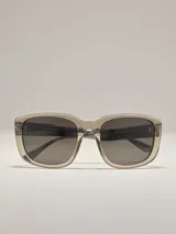 Lentes de sol William con armazón rectangular de acetato transparente en tono gris y cristales oscuros.