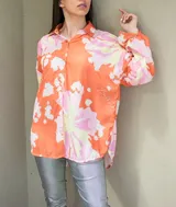 Camisa oversize con estampado floral abstracto en tonos naranja, rosado y amarillo, de manga larga y cierre frontal con botones.