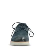 Zapato de estilo casual tipo derby, confeccionado en cuero azul marino con acabado gamuzado. Presenta detalles de costuras decorativas y perforaciones tipo brogue en los laterales, con un detalle en cuero color suela en el talón. Cuenta con cordones al tono y una suela de EVA flexible en color gris claro con tecnología de amortiguación.
