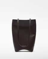 Bolso tipo shopper vertical de cuero color marrón oscuro, con asas largas para el hombro, base rígida curvada, un compartimento y bolsillo interior.