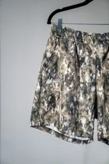 Short deportivo con estampado camuflado en tonos verde, marrón y blanco. Confeccionado en tela suave y ligera con abertura en los costados para mayor comodidad.