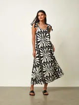 Vestido midi negro con estampado gráfico en blanco, de corte amplio y escote redondo con tirantes anudados en los hombros.