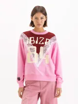 Buzo de cuello redondo en color rosado, con un diseño combinado en el pecho que incluye un panel superior bordó, detalles de encaje y la inscripción "IBIZA 84" en tono beige.