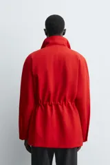 Parka de corte regular confeccionada en tejido técnico repelente al agua. Presenta cuello subido ajustable con cordón, cierre frontal con cremallera oculta por solapa con botones a presión, bolsillos de plastrón con solapa en la cadera y cintura ajustable con cordón. Incluye un forro interior acolchado desmontable.