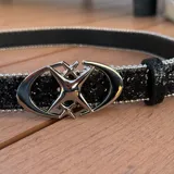 Cinturón plateado con brillos y hebilla metálica con diseño de doble círculo entrelazado.