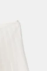 Falda midi blanca de tiro alto con pliegues verticales que le dan volumen y movimiento.