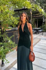 Vestido largo verde oscuro de terciopelo y satén, con escote halter pronunciado y diseño ajustado en el torso con caída fluida en la falda.