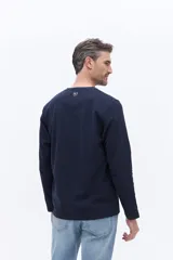 Remera tipo henley de manga larga en color azul marino, confeccionada en algodón con textura. Presenta una cartera con botones en el cuello y un pequeño logo bordado en el pecho.