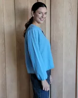 Blusa celeste de manga larga con escote en V y detalle bordado en el cuello.