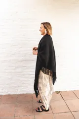 Ruana de lana color negro con terminación de flecos en los bordes y diseño con caída en picos en la espalda.