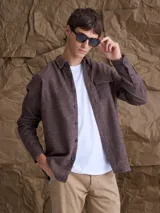 Overshirt de textura tipo tweed en color marrón, con cuello clásico, cierre frontal de botones y bolsillo en el pecho.
