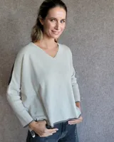 Sweater de corte holgado con cuello en V, confeccionado en lana lambswool. Presenta un diseño bicolor con cuerpo en tono claro y detalles en contraste en los bordes y mangas.