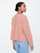 Remera de manga larga color salmón, con cuello redondo y corte holgado.