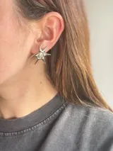 Aros caravanas plateados con diseño de estrella de mar y detalle en espiral en el centro.