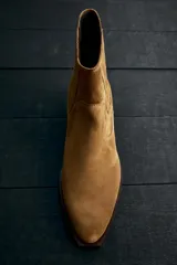 Bota de piel color marrón claro, estilo cowboy, con caña corta, puntera en punta y tacón cubano.